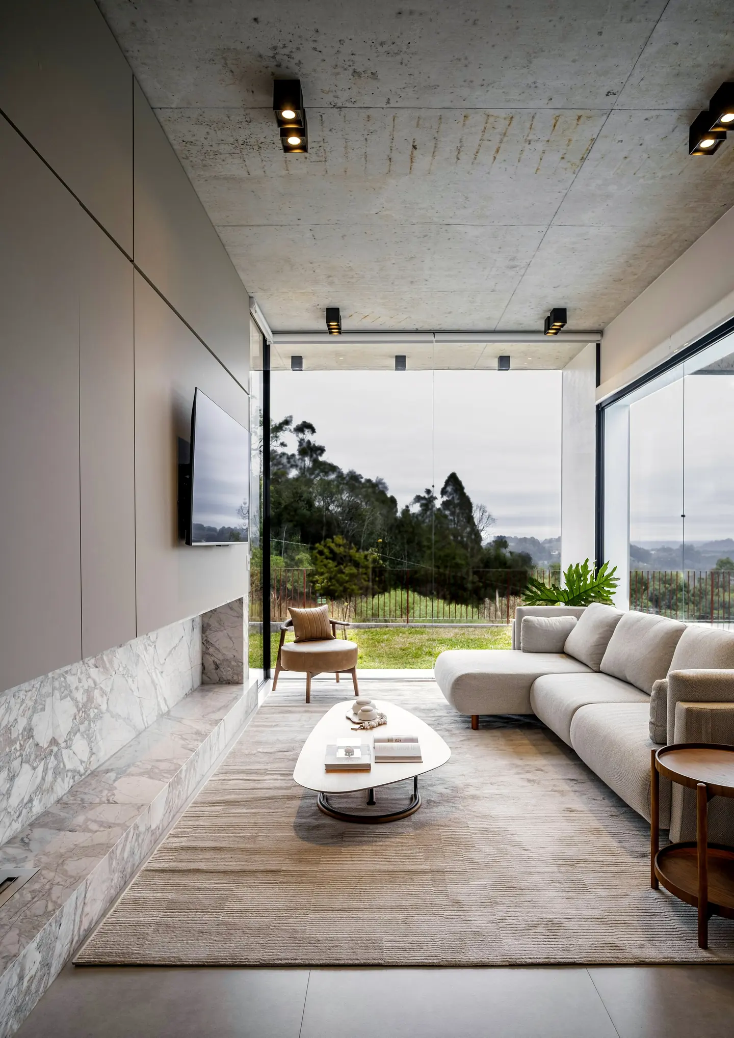 A sitting room opening through a glass wall to the garden