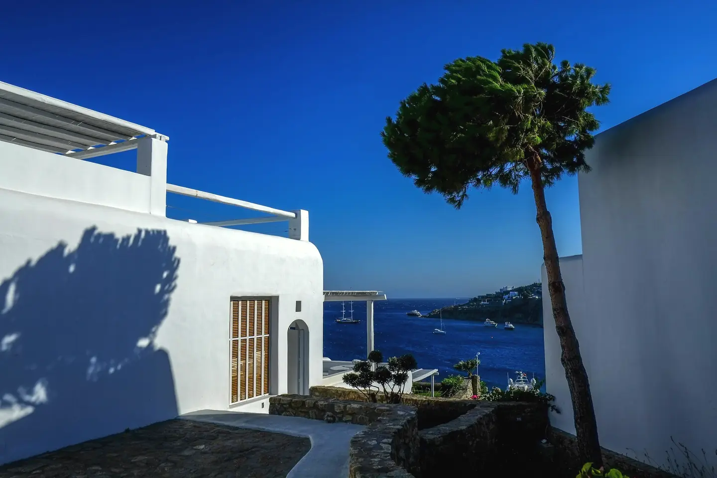 A white Cycladic house above a bay of moored yachts
