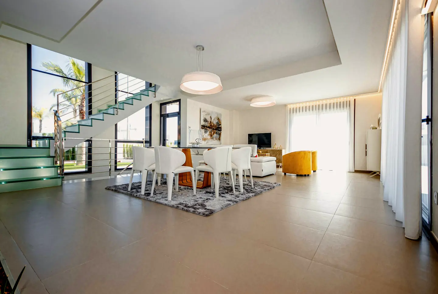 A bright open living and dining room with a glass stair