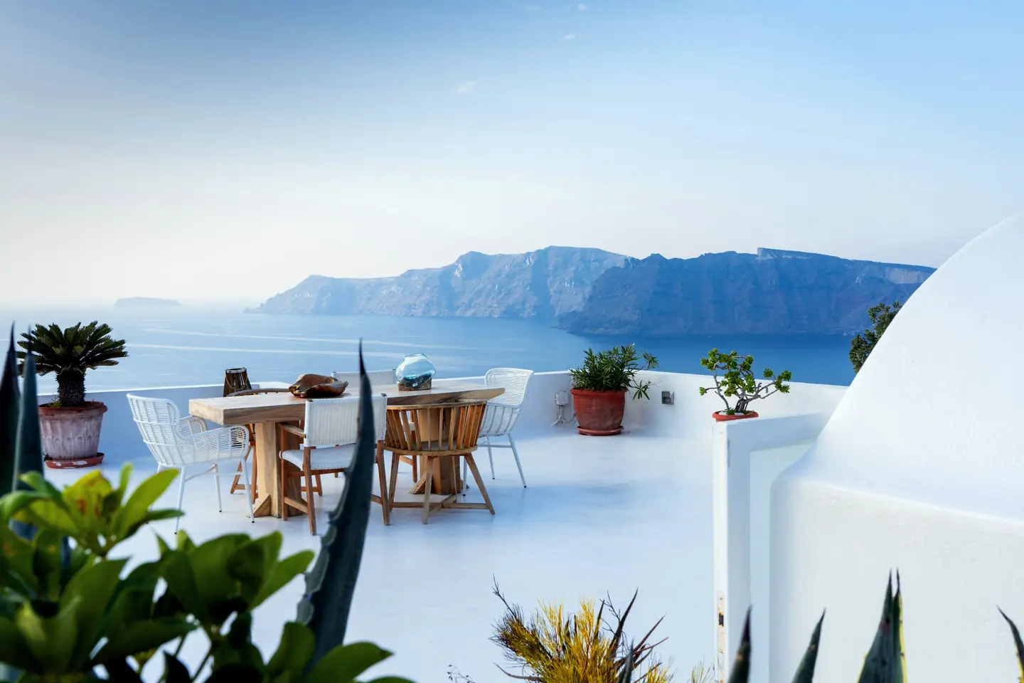 A white terrace with a table and chairs above the sea